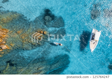 Aerial view of a woman on sup board, boat nad blue sea in summer Aerial view of a woman on sup board, boat nad blue sea in summer 125764247