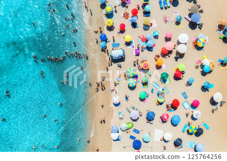 Aerial view of colorful umbrellas on beach, people in blue sea 125764256