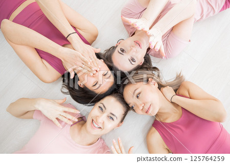 Top view of lying down Two Caucasian and two Asian women in sportswear.  125764259