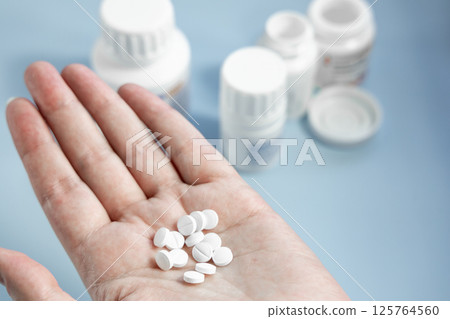 Human hand holding a handful of white pills Human hand holding a handful of white pills 125764560