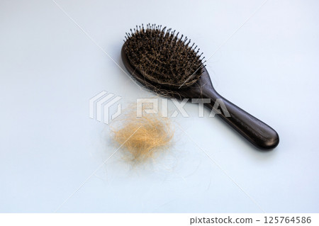Black hairbrush and a bunch of fallen hair. Hair loss concept 125764586