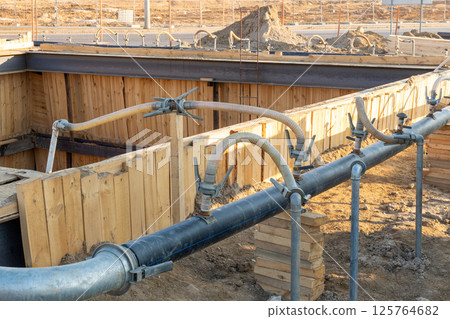 A close-up view of a series of flexible hoses connected to a pipe at a construction site 125764682