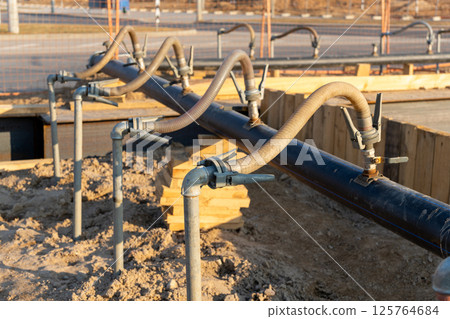 A close-up view of a series of flexible hoses connected to a pipe at a construction site A close-up view of a series of flexible hoses connected to a pipe at a construction site 125764684
