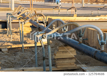 A close-up view of a series of flexible hoses connected to a pipe at a construction site A close-up view of a series of flexible hoses connected to a pipe at a construction site 125764686