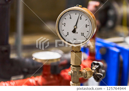 Close-up of a Brass Industrial Pressure Gauge Measuring in Bar, Connected to a Piping System Close-up of a Brass Industrial Pressure Gauge Measuring in Bar, Connected to a Piping System 125764944