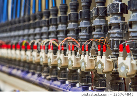 Close-up of an Organized Array of Solenoid Valves and Piping in an Industrial Fluid Control System 125764945