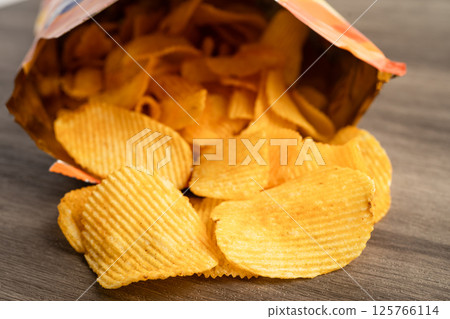 Potato chips, delicious BBQ seasoning spicy for crips, thin slice deep fried snack fast food in open bag. Potato chips, delicious BBQ seasoning spicy for crips, thin slice deep fried snack fast food in open bag. 125766114