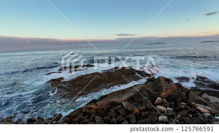 The Tranquil Ocean Waves Gently Crash Against the Rocky Shoreline at a Beautiful Sunset The Tranquil Ocean Waves Gently Crash Against the Rocky Shoreline at a Beautiful Sunset 125766591