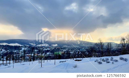A picturesque Snowy Winter Landscape featuring a Dramatic Cloudy Sky above it all 125766592
