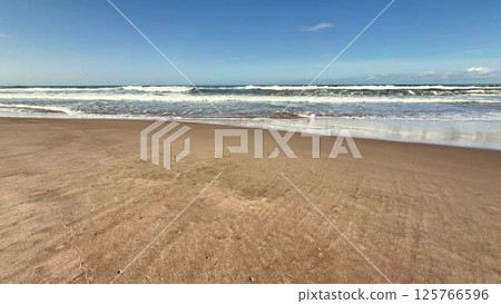 A Serene and Picturesque Beach Landscape Featuring Gentle Waves and Bright Clear Skies 125766596