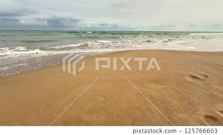A beautifully serene seascape featuring a sandy beach with gentle waves softly lapping at the shore A beautifully serene seascape featuring a sandy beach with gentle waves softly lapping at the shore 125766603