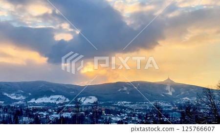 Experience a breathtaking winter sunset that lights up the snowy mountains in beauty 125766607