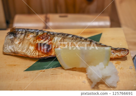 March 26 2025 Grilled Mackerel with Lemon Wedges on a Wooden Plate 125766691