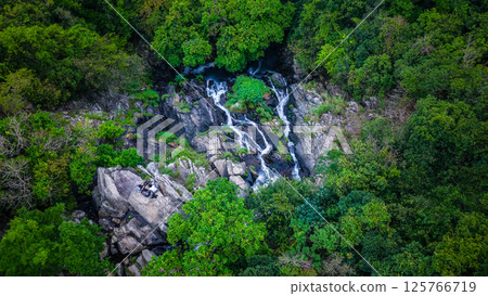 View of a Serene Waterfall Cascading Through Lush Green Forest 125766719