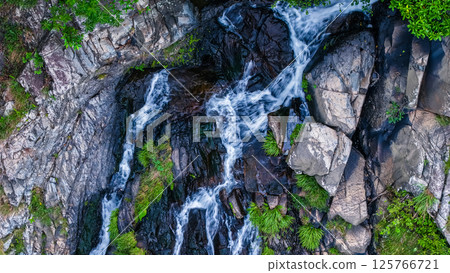 View of a Serene Waterfall Cascading Through Lush Green Forest 125766721