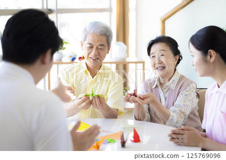 Care image: Seniors and caregivers folding origami 125769096