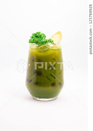 green vegetable juice with ice served in glass and garnished with fresh kale and ginger slice on white background. High quality photo 125769926