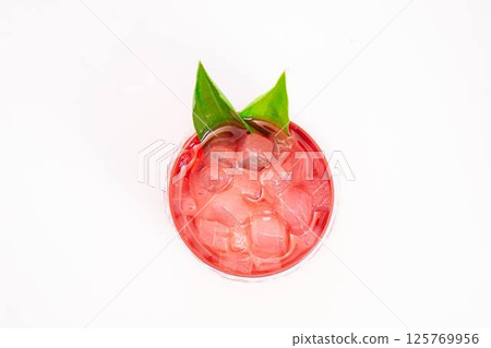 red berry cocktail served in clear glass with crushed ice and green tropical leaves isolated on white background. High quality photo 125769956