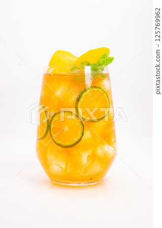 yellow peach and orange citrus drink with fresh mint leaves and ice served in clear glass on white background. High quality photo 125769962