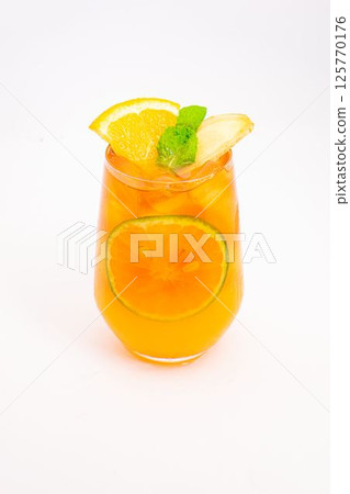 refreshing orange citrus cocktail with sliced lemon and mint leaves served in clear glass over ice on white background. High quality photo 125770176