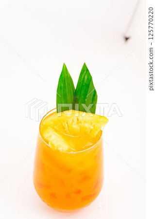 orange citrus cocktail with tropical leaf garnish served in transparent glass over ice on clean white background. High quality photo orange citrus cocktail with tropical leaf garnish served in transparent glass over ice on clean white background. High quality photo 125770220