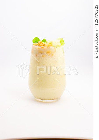 creamy banana smoothie topped with cereal flakes and fresh mint served in clear glass on white background. High quality photo creamy banana smoothie topped with cereal flakes and fresh mint served in clear glass on white background. High quality photo 125770225