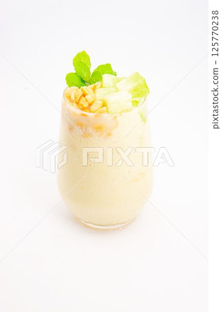 creamy banana smoothie topped with cereal flakes and fresh mint served in clear glass on white background. High quality photo creamy banana smoothie topped with cereal flakes and fresh mint served in clear glass on white background. High quality photo 125770238