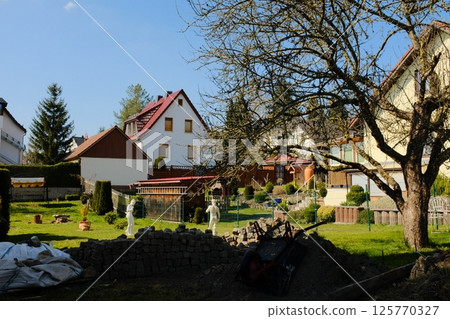 european village garden decorated with white easter bunny statues and spring greenery under clear sky. High quality photo 125770327