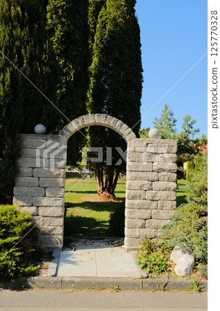 european village garden decorated with white easter bunny statues and spring greenery under clear sky. High quality photo 125770328