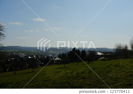 wide open green countryside field under clear blue sky with distant trees and rolling hills in peaceful rural landscape. High quality photo wide open green countryside field under clear blue sky with distant trees and rolling hills in peaceful rural landscape. High quality photo 125770411