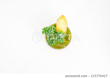 green vegetable juice with ice served in glass and garnished with fresh kale and ginger slice on white background. High quality photo green vegetable juice with ice served in glass and garnished with fresh kale and ginger slice on white background. High quality photo 125770427