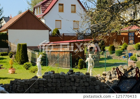 european village garden decorated with white easter bunny statues and spring greenery under clear sky. High quality photo european village garden decorated with white easter bunny statues and spring greenery under clear sky. High quality photo 125770433