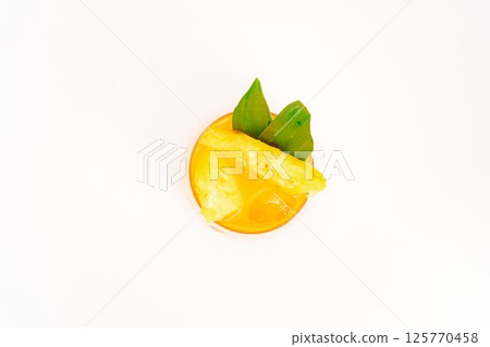orange citrus cocktail with tropical leaf garnish served in transparent glass over ice on clean white background. High quality photo 125770458