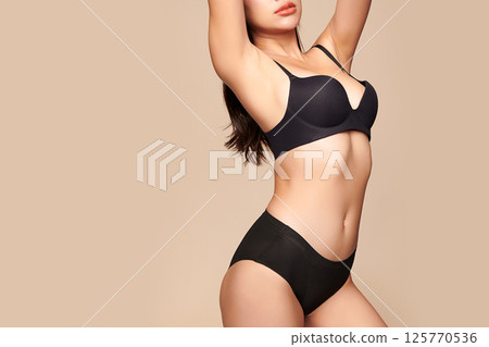 Confident beautiful young asian woman posing in black lingerie on beige background, Perfect body, Confident beautiful young asian woman posing in black lingerie on beige background, Perfect body, 125770536