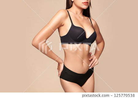 Confident beautiful young asian woman posing in black lingerie on beige background, Perfect body, 125770538