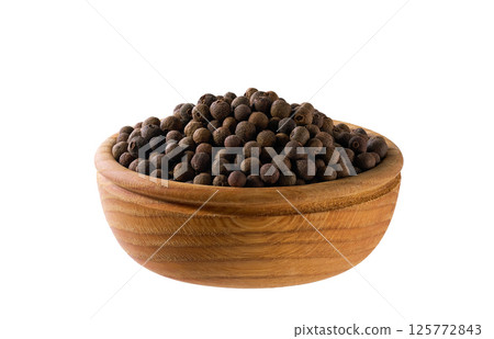 allspice or Jamaican pepper seeds in a wooden bowl isolated on white background. allspice or Jamaican pepper seeds in a wooden bowl isolated on white background. 125772843