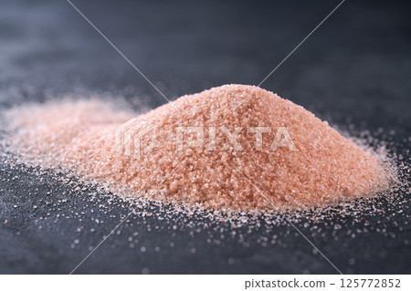 Pile of pink himalayan salt on a black stone table, selective focus. Pile of pink himalayan salt on a black stone table, selective focus. 125772852