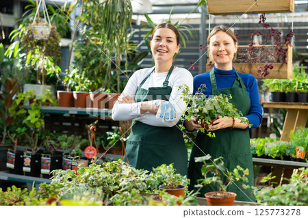 Adult woman and young woman posing in flower shop Adult woman and young woman posing in flower shop 125773278