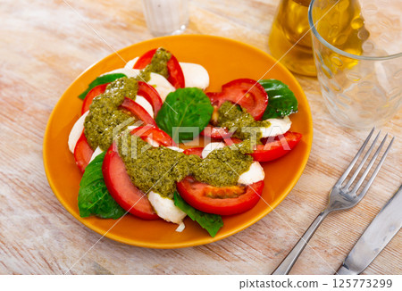 Caprese with basil leaves and pesto sauce on table Caprese with basil leaves and pesto sauce on table 125773299