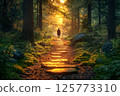 Back view of a person walking along a forest path illuminated by the morning sun 125773310