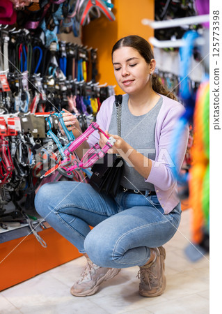Young woman choosing collar her dog at pet store Young woman choosing collar her dog at pet store 125773398