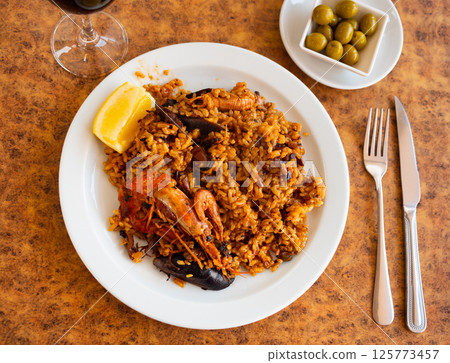 Seafood paella with mussels, calamari and prawns served with lemon Seafood paella with mussels, calamari and prawns served with lemon 125773457