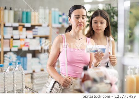 Mother with teenage daughter choosing an ointment 125773459