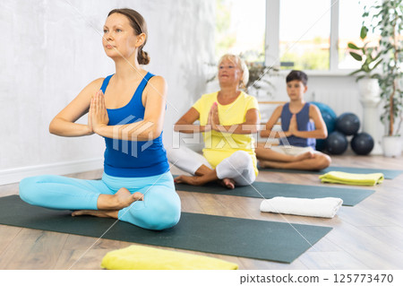Group of people generation on mats doing yoga exercise lord of fishes pose. Group of people generation on mats doing yoga exercise lord of fishes pose. 125773470