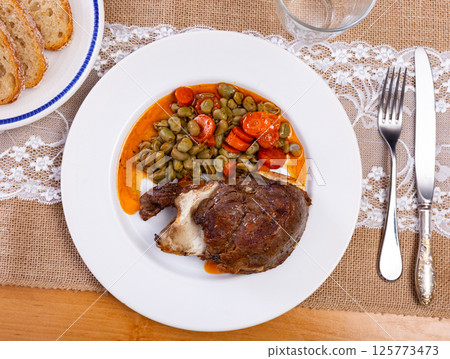 Pork cheeks served with beans on plate 125773473