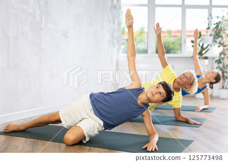 Mother, grandmother and teen son do Vasishthasana, side plank pose 125773498