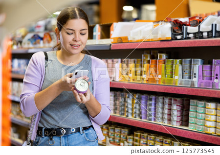 Young woman scanning label on tin can of wet food in pet store Young woman scanning label on tin can of wet food in pet store 125773545
