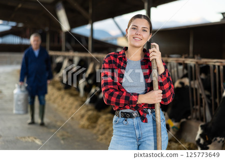 Portrait of positive woman farmer in cowshed Portrait of positive woman farmer in cowshed 125773649