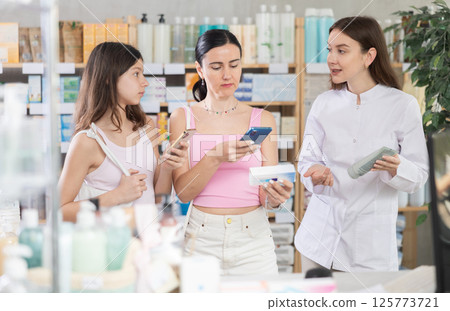 Mother and daughter scan ointment qr code with pharmacist 125773721