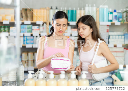 Woman with teen girl choose buy panty liners at pharmacy 125773722